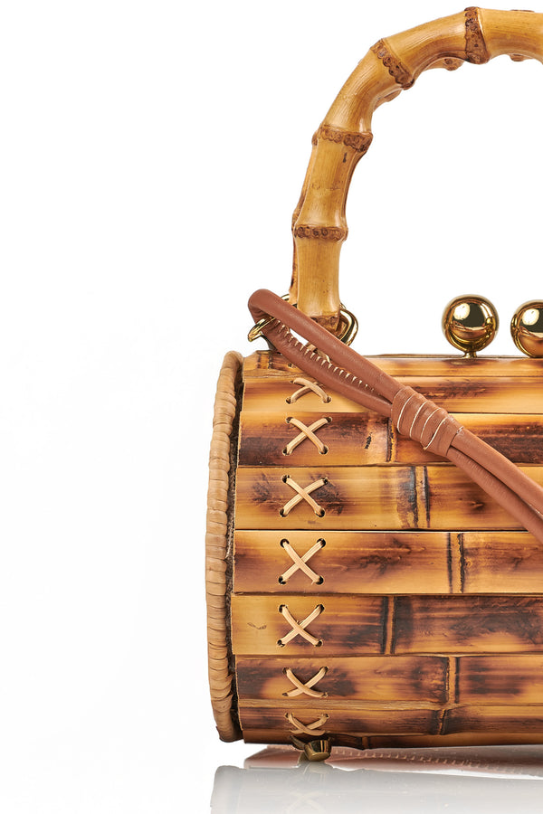 Bolsa estruturada em bambu natural com alça arredondada também em bambu, fecho metálico duplo em dourado e costura lateral em detalhe cruzado.