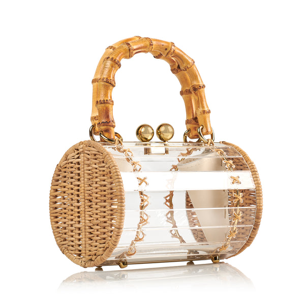 Bolsa box em acrílico transparente com laterais em rattan, detalhe de costura em X dourado, alça rígida em bambu e fecho esférico metálico dourado.