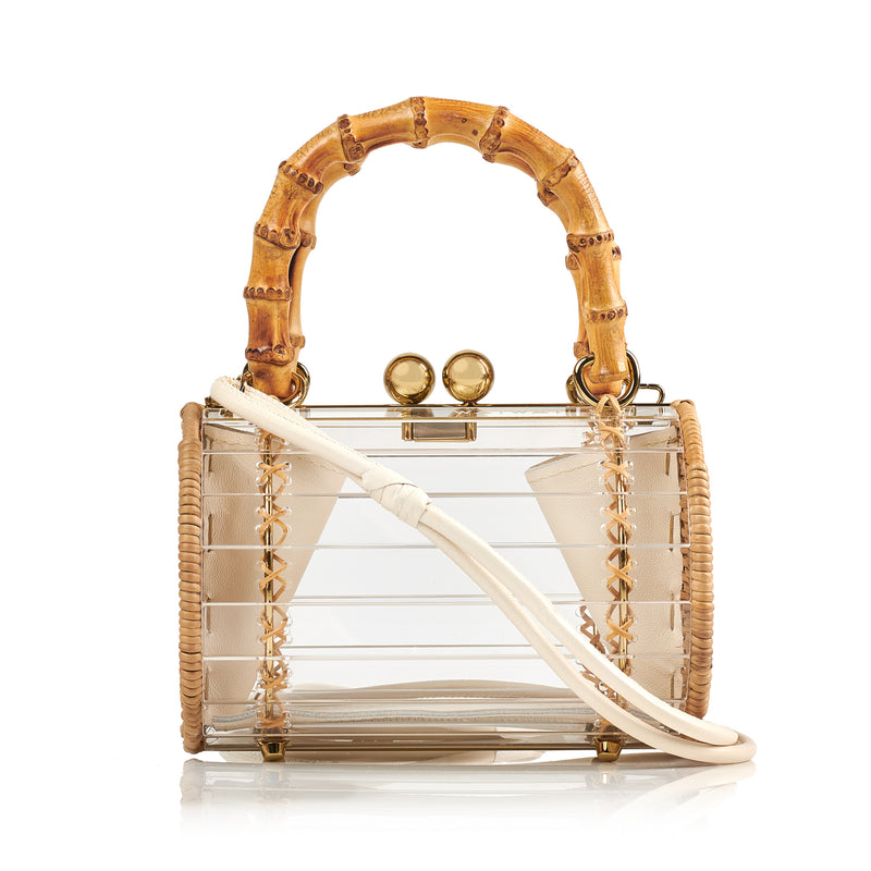 Bolsa box em acrílico transparente com laterais em rattan, detalhe de costura em X dourado, alça rígida em bambu e fecho esférico metálico dourado.