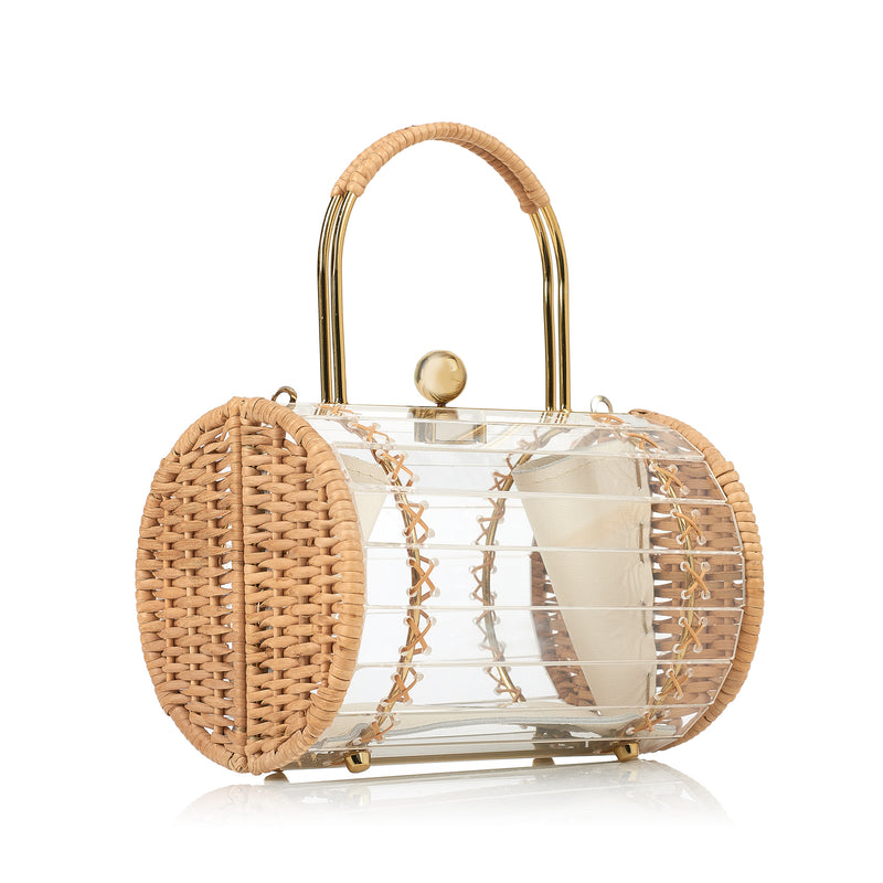 Bolsa box estruturada em acrílico transparente com laterais em rattan, detalhe de costura em X dourado, alça rígida metálica com revestimento em rattan e fecho esférico dourado.
