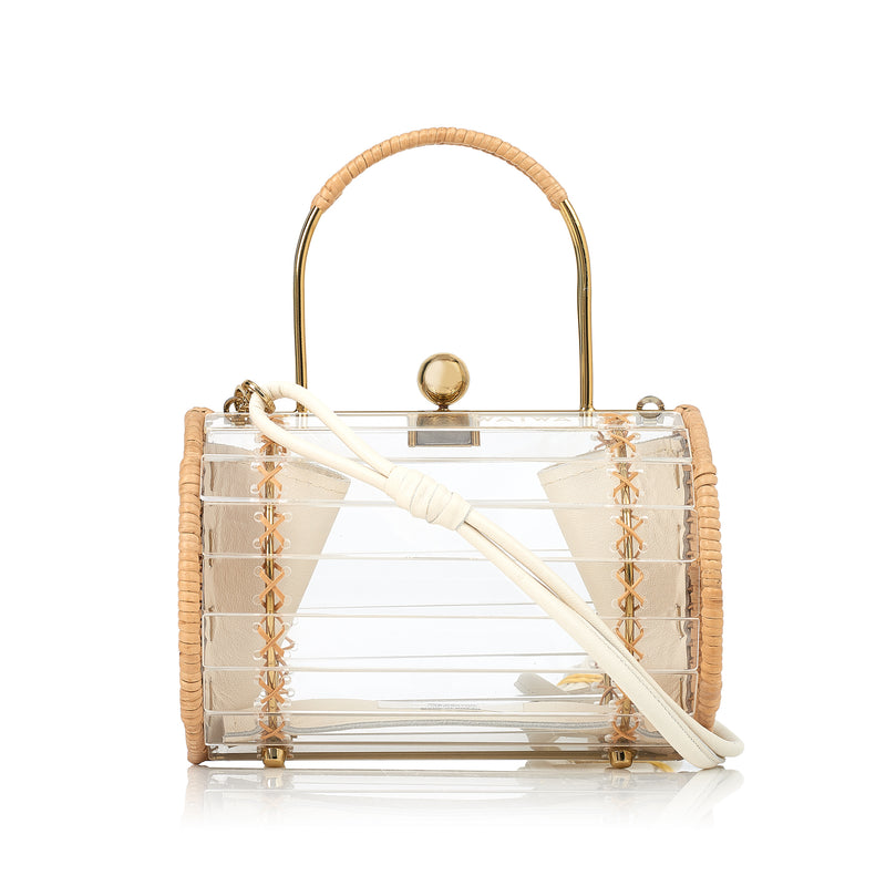 Bolsa box estruturada em acrílico transparente com laterais em rattan, detalhe de costura em X dourado, alça rígida metálica com revestimento em rattan e fecho esférico dourado.