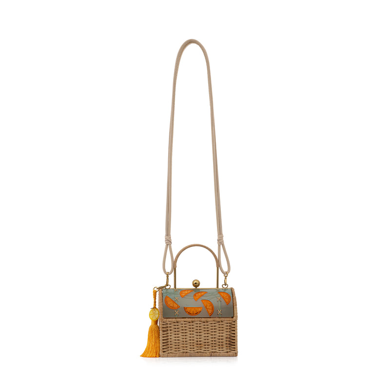 Bolsa box em palha natural com parte superior em acrílico fosco esverdeado, decorado com fatias de laranja em relevo. Possui alça estruturada, fecho dourado e tassel amarelo com detalhe em acrílico transparente.