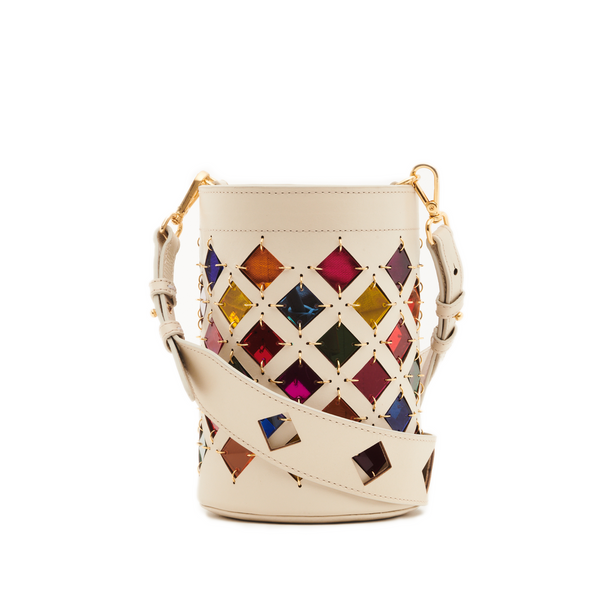 Bolsa bucket em couro branco com recortes geométricos em losangos, revelando fundo colorido em tons de arco-íris. Alça longa ajustável com detalhes vazados e ferragens douradas.