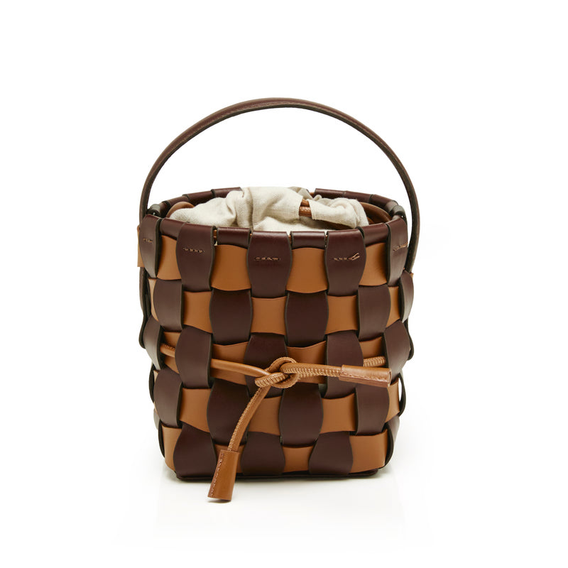 Bolsa bucket estruturada em couro trançado marrom e caramelo, com alça única e saquinho interno em tecido cru.