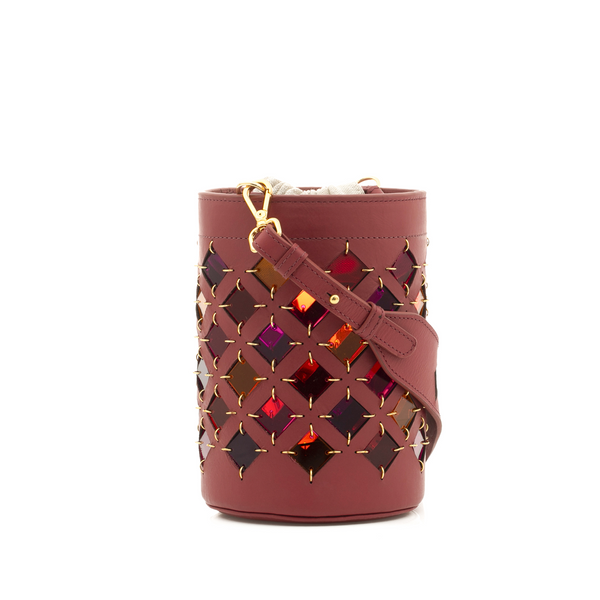Bolsa bucket em couro vinho com recortes geométricos em losangos, revelando detalhes internos coloridos em efeito espelhado, com alça longa ajustável e fecho com cordão interno.