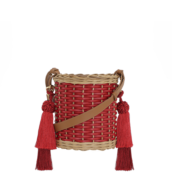 Bolsa bucket em palha trançada com detalhes em vermelho, alça longa em couro caramelo e tassels grandes em vermelho.