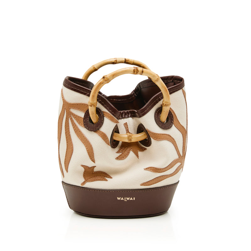 Bolsa bucket pequena em tecido cru com bordados marrons, base em marrom sólido e alça estruturada em bambu.