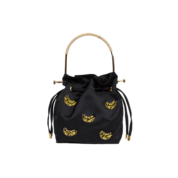 Bolsa bucket em seda preta com aplicações bordadas de bananas em cristais amarelos, alça estruturada em metal dourado com detalhe em rattan e fechamento por cordão ajustável.