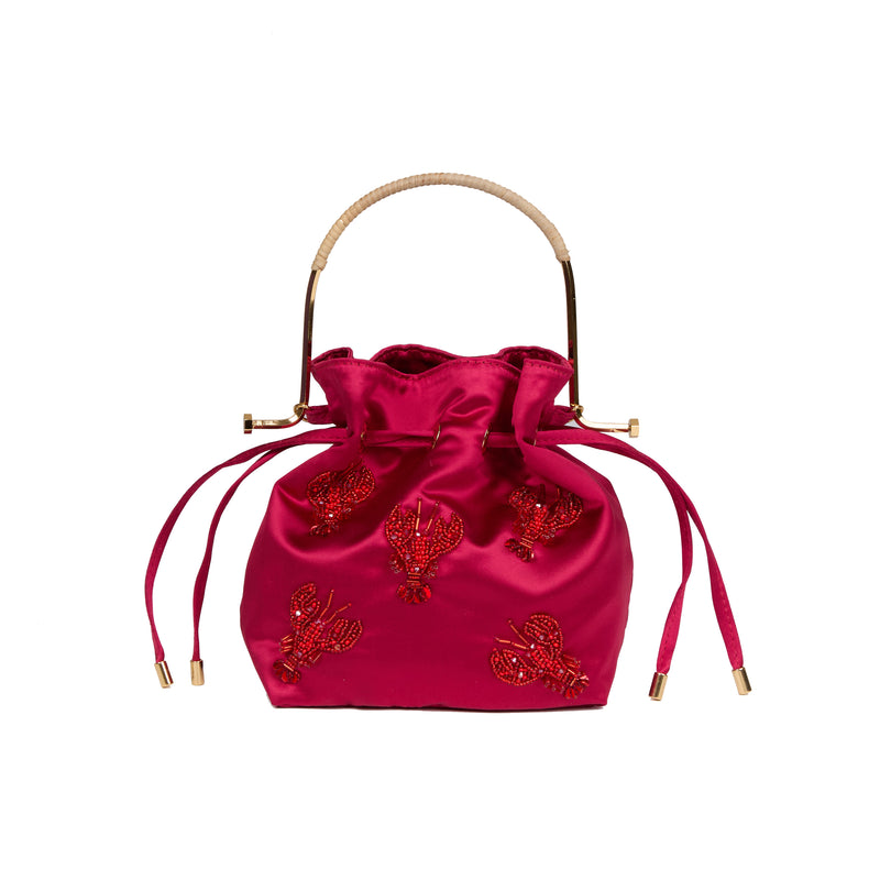 Bolsa bucket em seda rosa intensa com bordado de lagostas em miçangas vermelhas, alça estruturada em metal dourado com detalhe em rattan e fechamento por cordão ajustável.