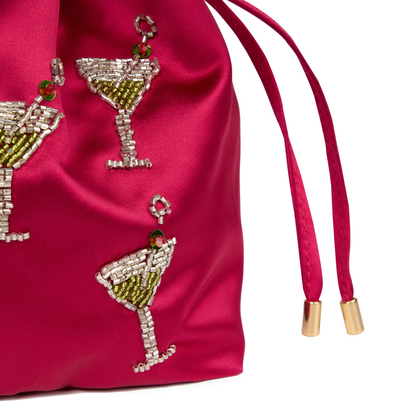 Bolsa bucket em seda rosa intensa, com taças de cocktail bordadas em cristais, detalhe de alça dourada com rattan e fecho em cordão.