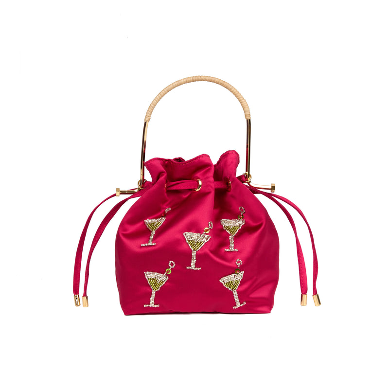 Bolsa bucket em seda rosa vibrante com aplicações bordadas de taças de cocktail decoradas com cristais, alça estruturada em metal dourado com detalhe em rattan e fechamento por cordão ajustável.