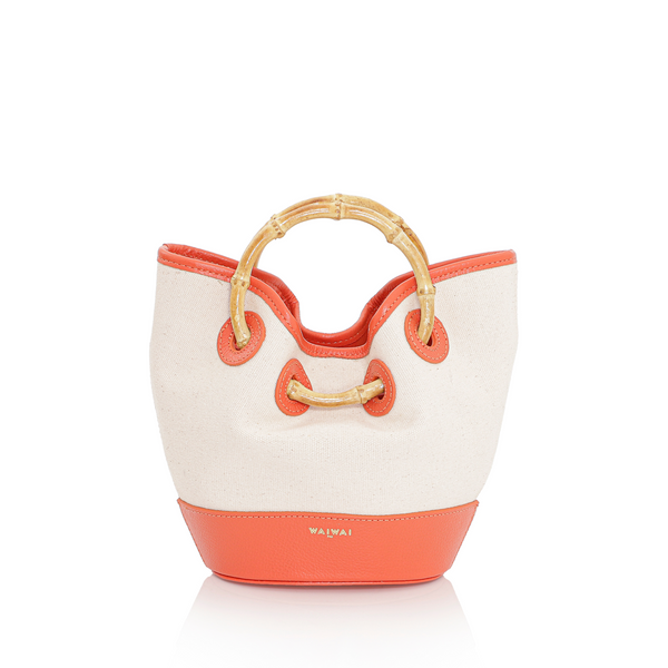 Bolsa em canvas cru com base e detalhes em couro laranja, alça curta em bambu e design estruturado.