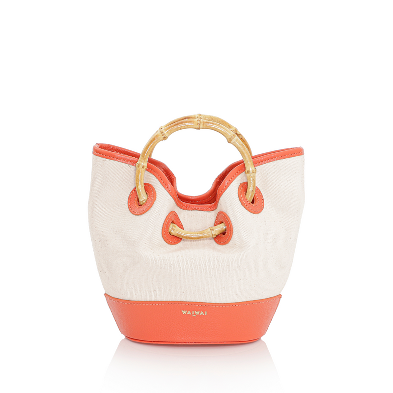 Bolsa em canvas cru com base e detalhes em couro laranja, alça curta em bambu e design estruturado.