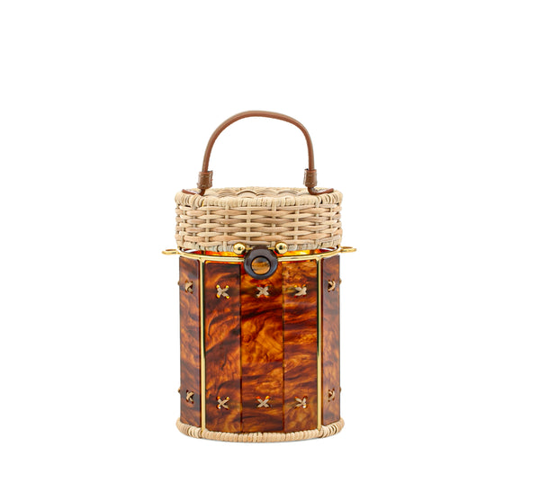 Bolsa cilíndrica estruturada em rattan e acrílico marmorizado em tons de âmbar, com fecho em metal dourado e alça curta em couro marrom.