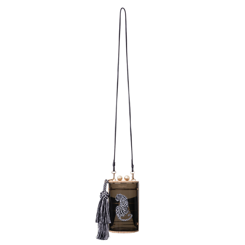 Bolsa clutch estruturada em acrílico preto translúcido, acabamento em rattan natural, estampa de onça branca central e franja longa em seda preta e branca, com fecho em esferas douradas.