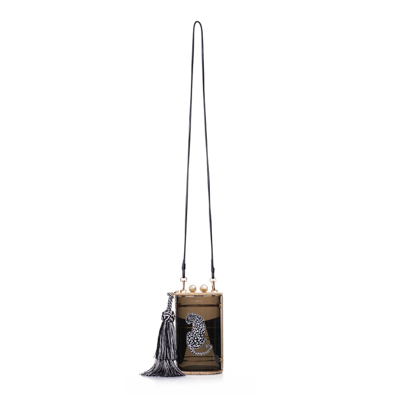 Bolsa clutch estruturada em acrílico preto translúcido, acabamento em rattan natural, estampa de onça branca central e franja longa em seda preta e branca, com fecho em esferas douradas.