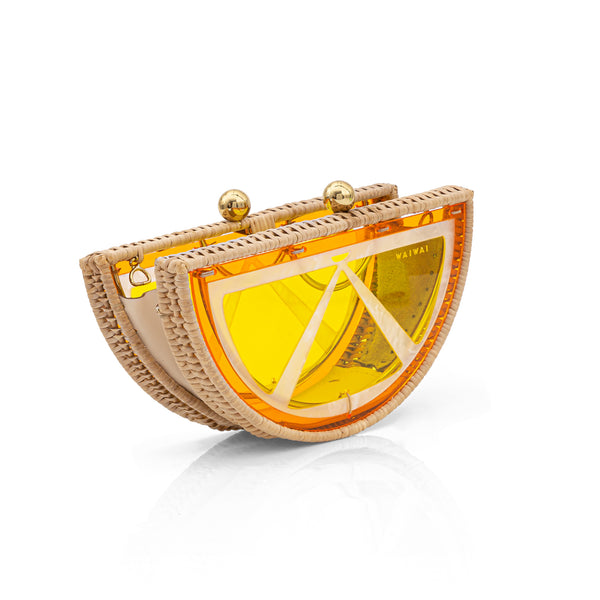 Clutch pequena em formato de meia-lua, com design inspirado em fatia de laranja, estruturada em rattan e acrílico amarelo translúcido com fecho dourado.