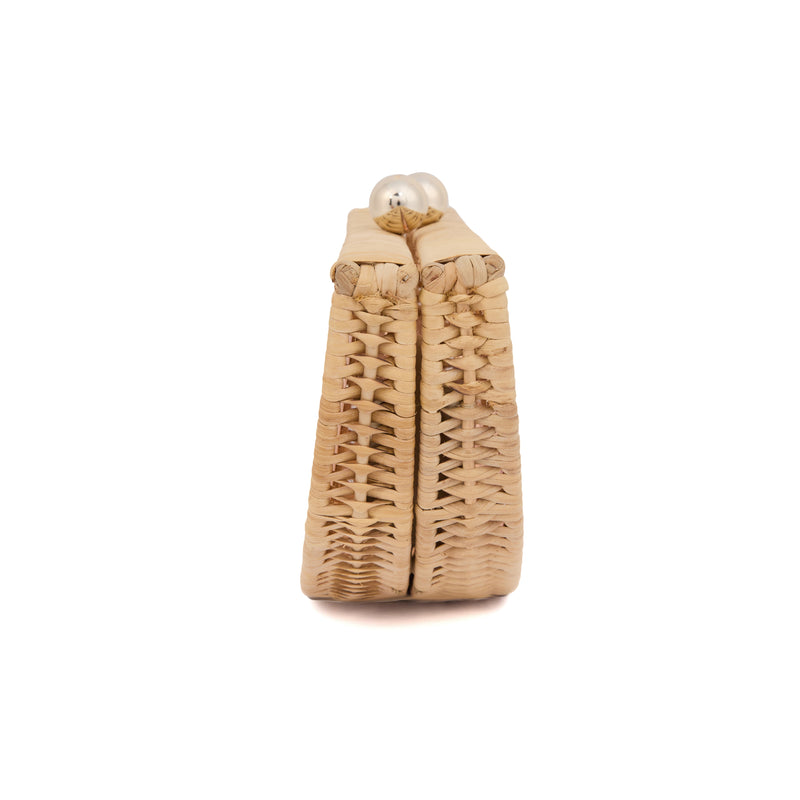 Clutch em formato meia-lua com estrutura em rattan e acrílico rosa translúcido, estampa estilizada de mulher deitada na praia com sol poente ao fundo, e fecho metálico dourado no topo.