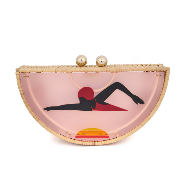 Clutch em formato meia-lua com estrutura em rattan e acrílico rosa translúcido, estampa estilizada de mulher deitada na praia com sol poente ao fundo, e fecho metálico dourado no topo.