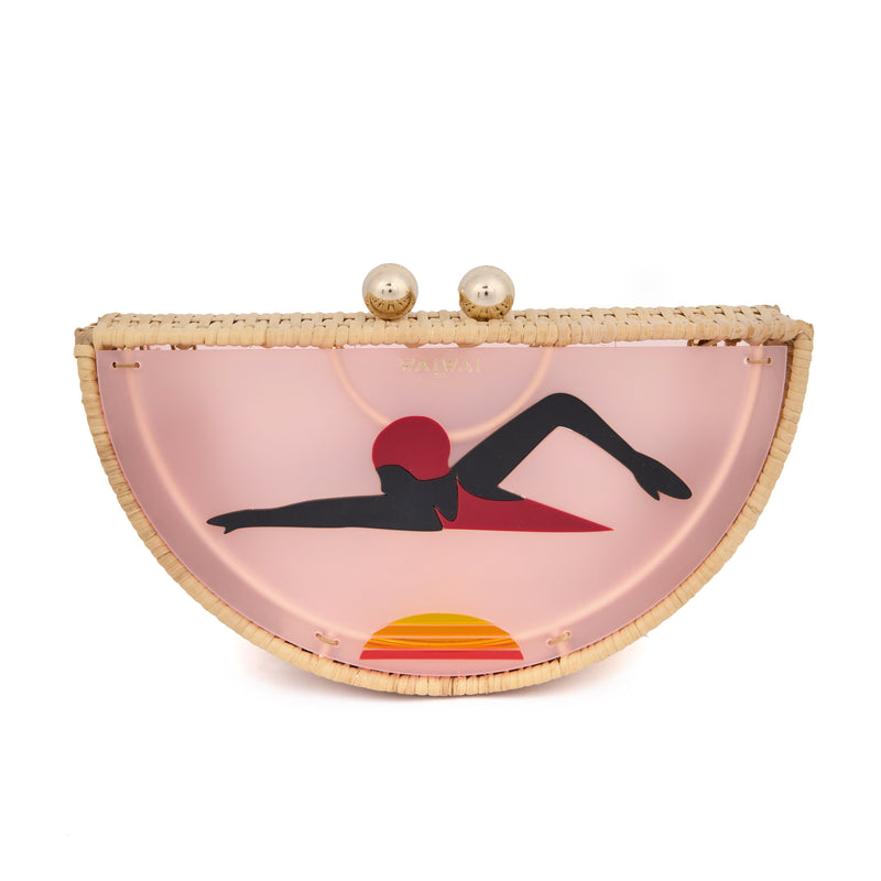 Clutch em formato meia-lua com estrutura em rattan e acrílico rosa translúcido, estampa estilizada de mulher deitada na praia com sol poente ao fundo, e fecho metálico dourado no topo.