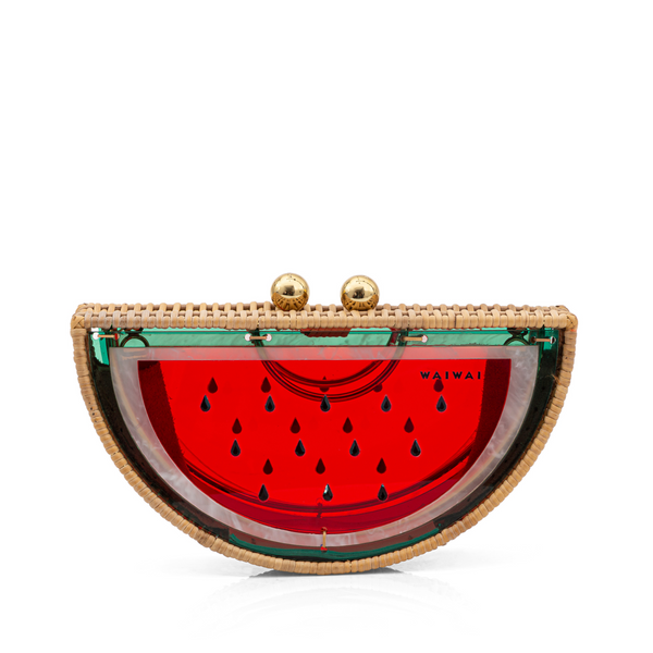 Bolsa clutch em formato de meia-melancia, estruturada em rattan e acrílico vermelho translúcido com detalhes em verde, sementes pretas e fecho dourado.