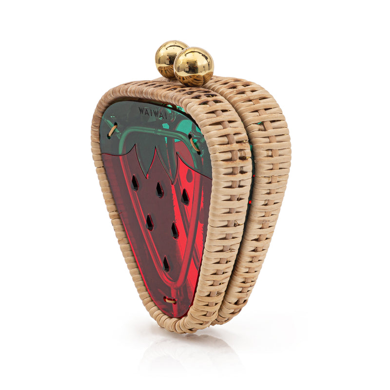 Bolsa clutch em formato de morango pequeno, estruturada em rattan e acrílico vermelho translúcido com detalhes verdes e fecho dourado.