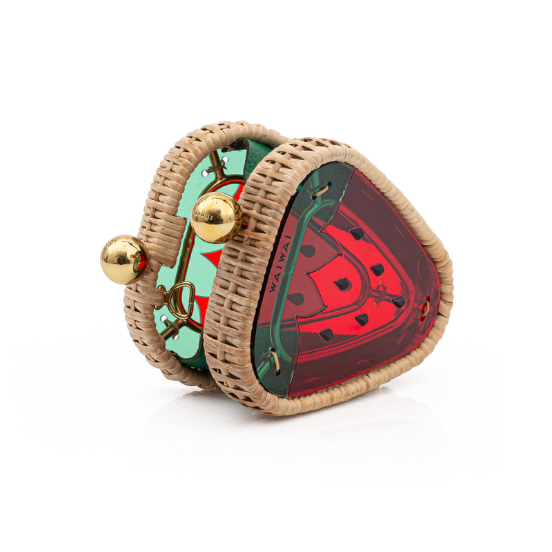 Clutch em formato de morango pequeno, estruturada em rattan e acrílico vermelho translúcido, finalizada com detalhes verdes e fecho dourado.