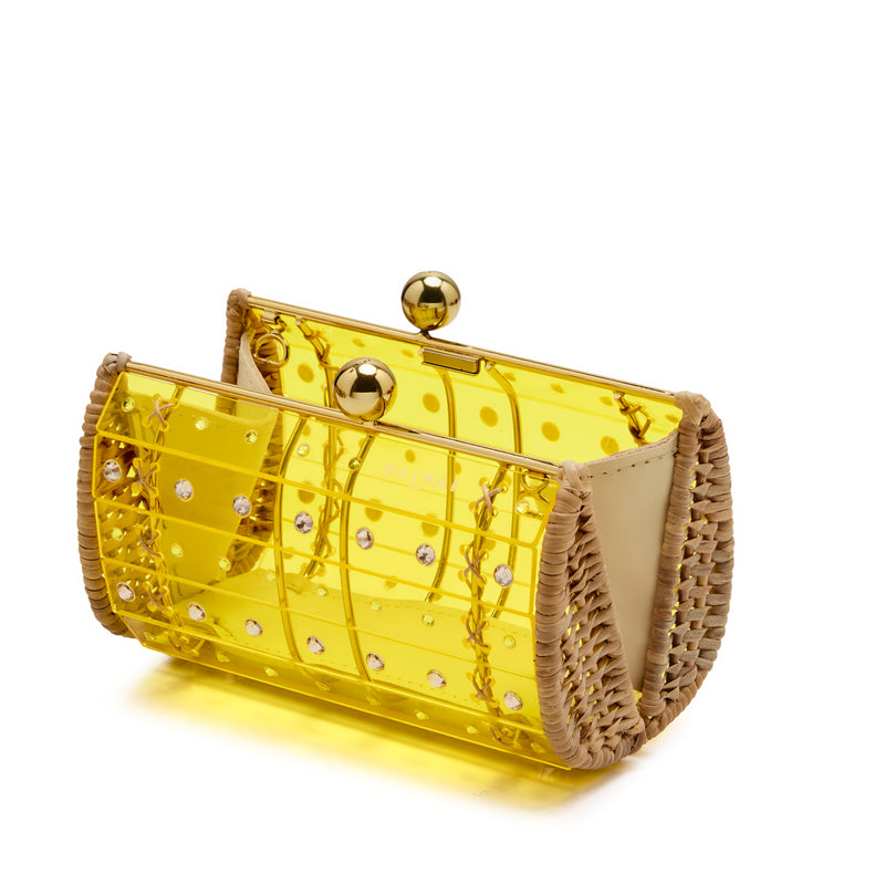Clutch estruturada em rattan com corpo em acrílico amarelo translúcido, aplicação de cristais circulares e fecho metálico dourado no topo.