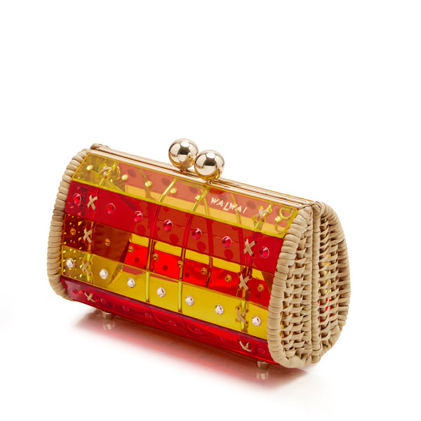 Clutch em rattan com corpo em acrílico translúcido listrado em vermelho e amarelo, detalhes em cristais e fecho metálico dourado no topo.