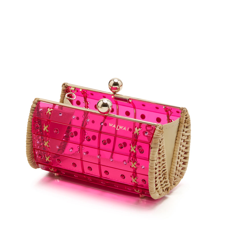 Clutch em rattan com corpo de acrílico rosa translúcido, aplicação de cristais redondos e fecho metálico dourado superior.