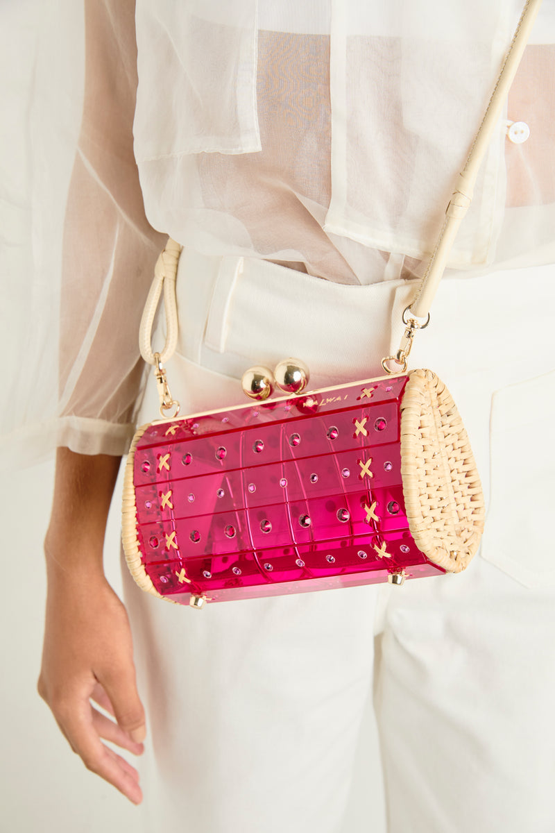 Clutch estruturada em rattan natural com corpo em acrílico rosa translúcido, aplicação de cristais e fecho metálico dourado.