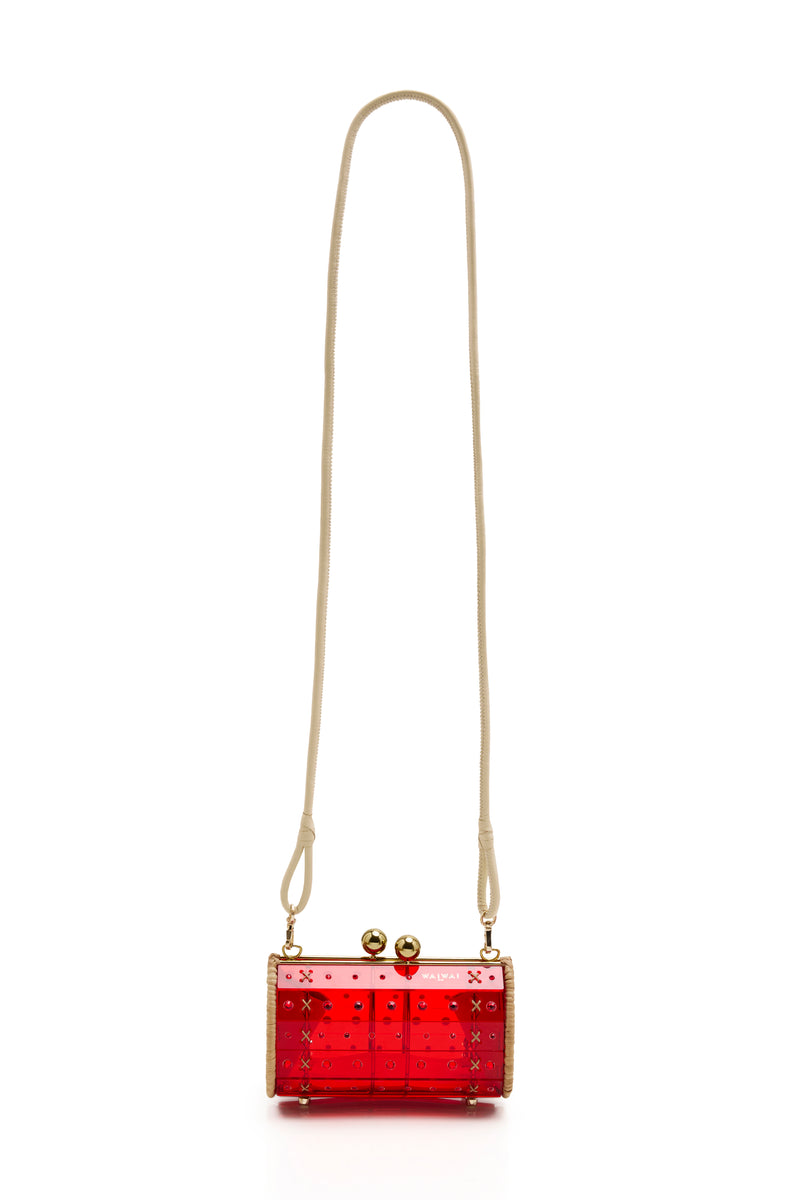 Clutch estruturada em rattan com corpo em acrílico vermelho translúcido, aplicação de cristais circulares e fecho metálico dourado no topo.