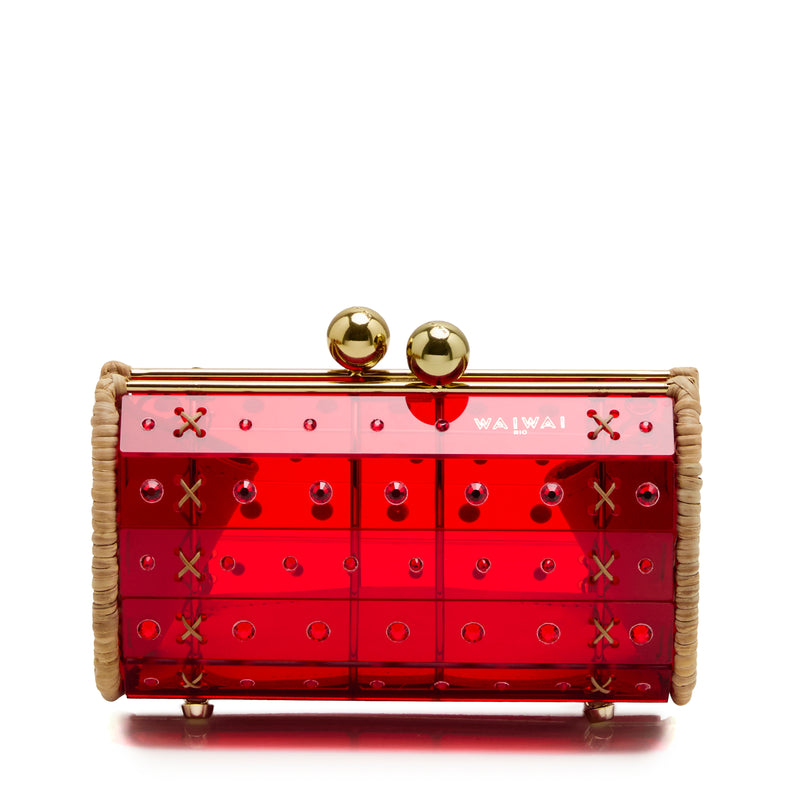 Clutch estruturada em rattan com corpo em acrílico vermelho translúcido, aplicação de cristais circulares e fecho metálico dourado no topo.