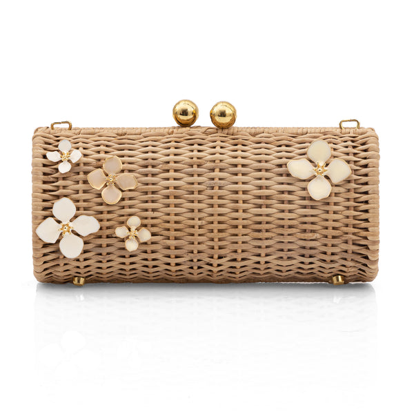 Clutch retangular em rattan natural com aplicações de flores esmaltadas em marfim e acabamentos dourados no fecho e pés metálicos.