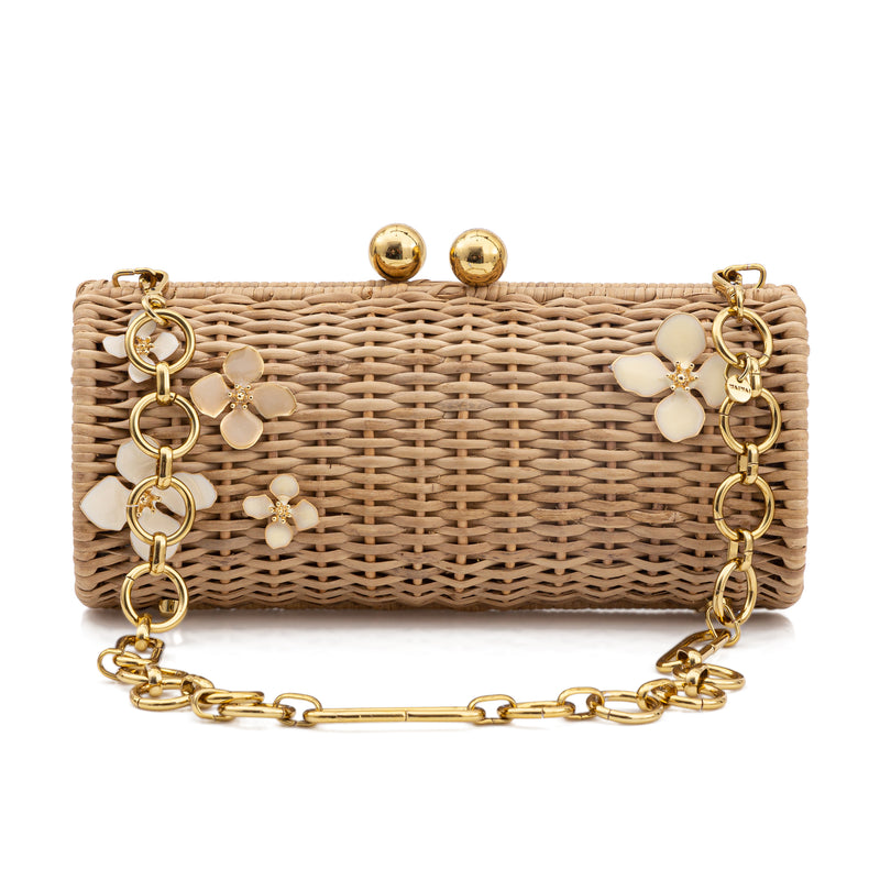 Clutch em rattan natural retangular com aplicações florais esmaltadas em tom marfim e detalhes dourados nos pés e fecho metálico.