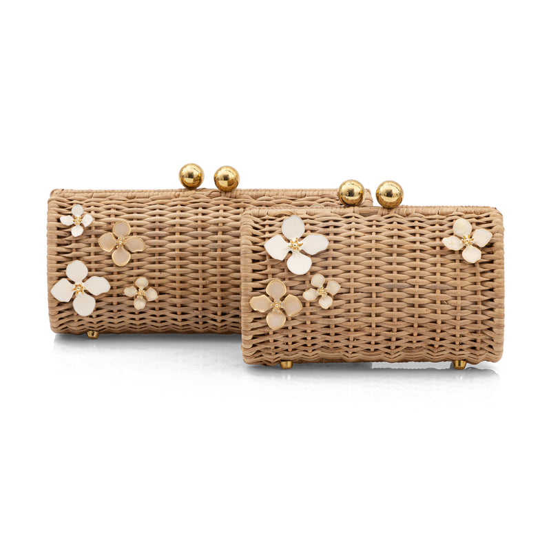 Bolsa clutch retangular em rattan natural, adornada com flores esmaltadas em marfim e detalhes metálicos dourados.