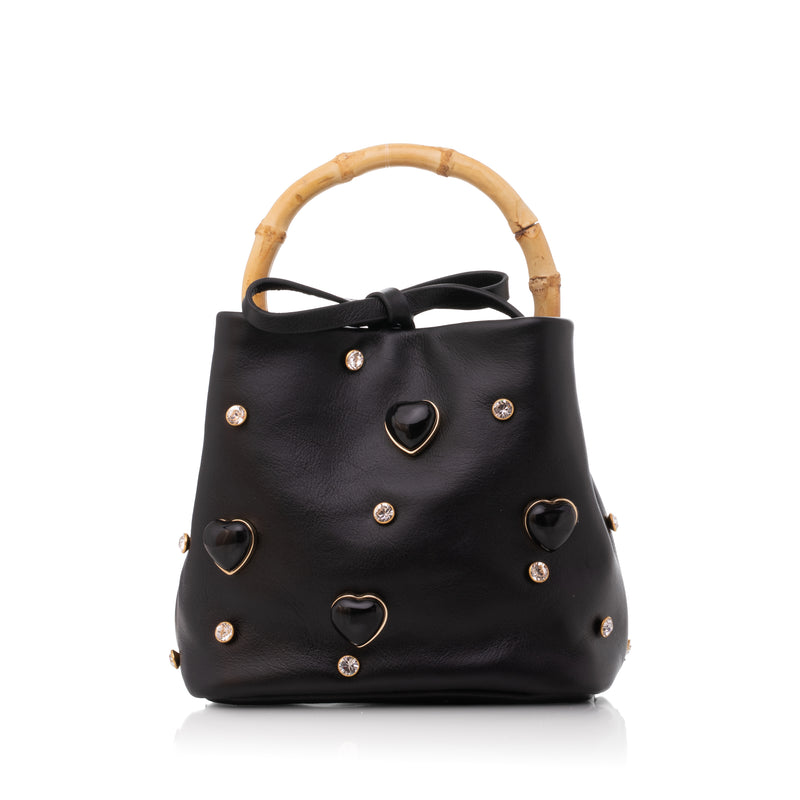 Bolsa autoral em couro preto com aplicações de corações e tachas douradas, alça superior em bambu.