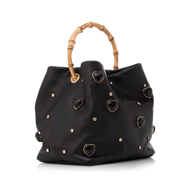 Bolsa artesanal em couro preto, decorada com corações metálicos e tachas douradas, alça de bambu.