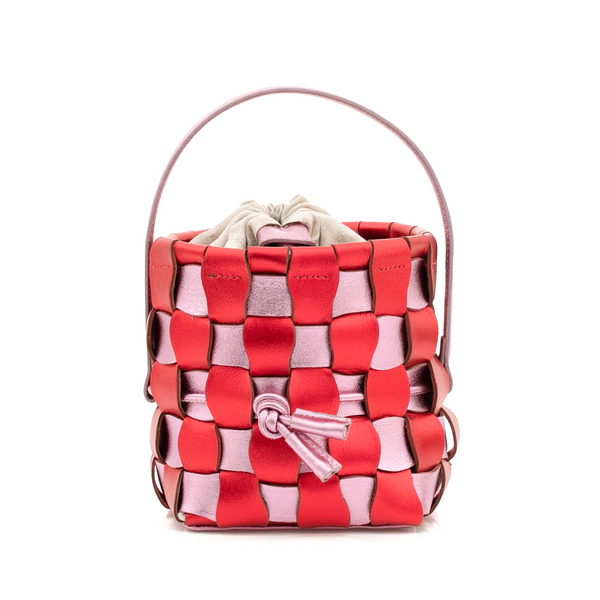 Bolsa bucket estruturada em couro trançado nas cores vermelho e rosa, com alça curta e fecho em cordão ajustável, exibindo visual moderno e artesanal.