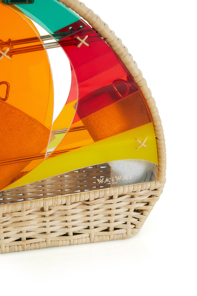 Bolsa em formato de barco à vela com base em rattan e velas em acrílico colorido em tons de laranja, vermelho, amarelo e verde, com detalhes em costura cruzada.