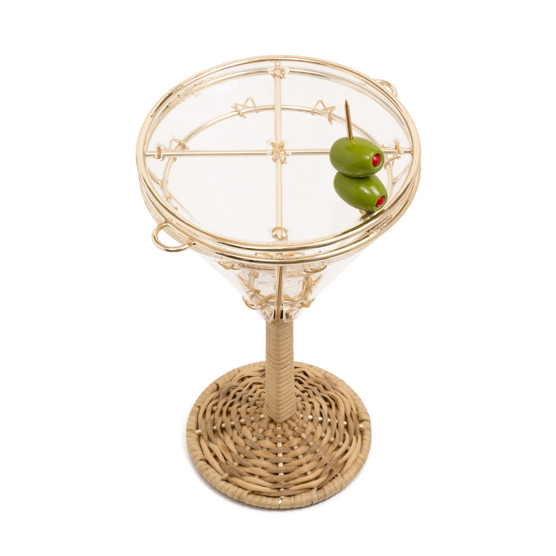 Bolsa em formato de taça de martini com base em rattan trançado, corpo em acrílico transparente com detalhes dourados e fecho divertido em formato de azeitona verde.