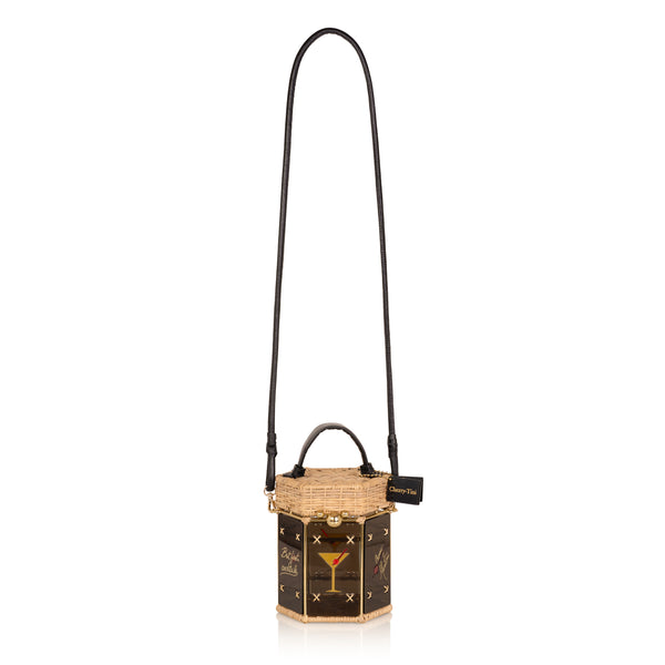 Bolsa hexagonal estruturada em rattan e acrílico preto translúcido, com estampa de taça de cocktail dourada com cereja vermelha ao centro, alça curta em couro preto e fecho metálico dourado.