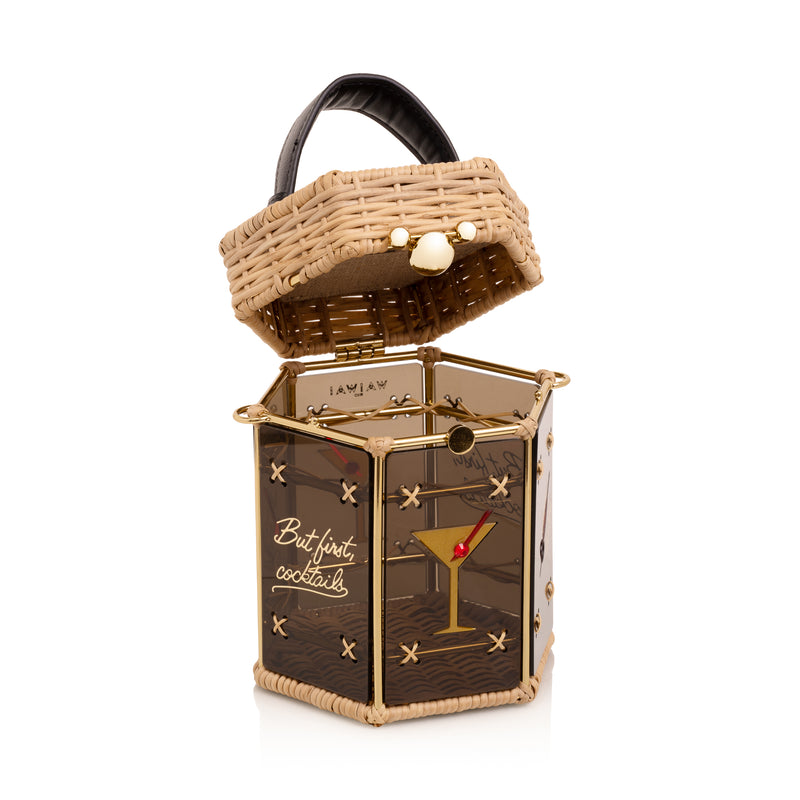 Bolsa hexagonal estruturada em rattan e acrílico preto translúcido, com estampa de taça de cocktail dourada com cereja vermelha ao centro, alça curta em couro preto e fecho metálico dourado.