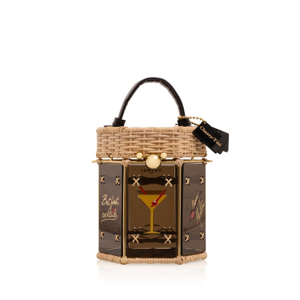 Bolsa hexagonal estruturada em rattan e acrílico preto translúcido, com estampa de taça de cocktail dourada com cereja vermelha ao centro, alça curta em couro preto e fecho metálico dourado.