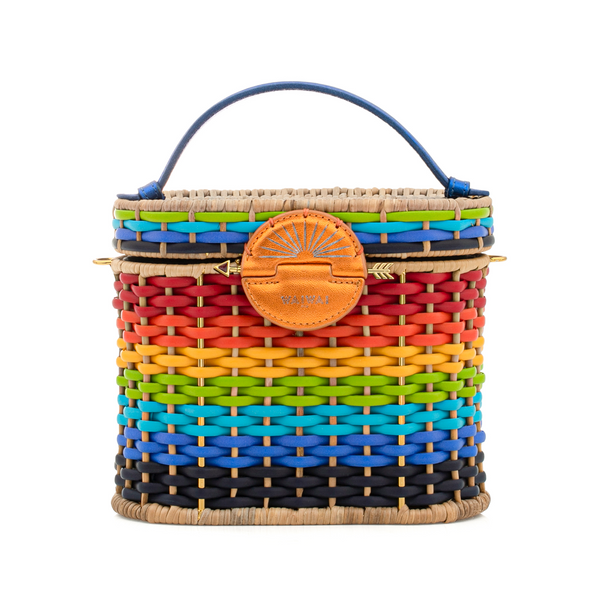 Bolsa estruturada em palha com trama multicolorida em degradê rainbow, detalhe em couro laranja no fecho redondo com símbolo de sol, alça curta em couro azul e acabamento em fibras naturais.