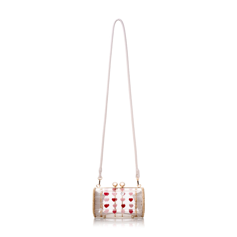 Bolsa cilíndrica em acrílico e vime trançado à mão, com detalhes de corações e fecho metálico dourado.