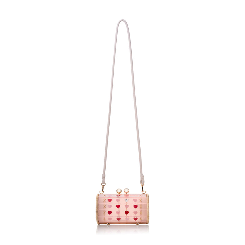 Bolsa cilíndrica em acrílico e vime trançado à mão, com detalhes de corações e fecho metálico dourado.