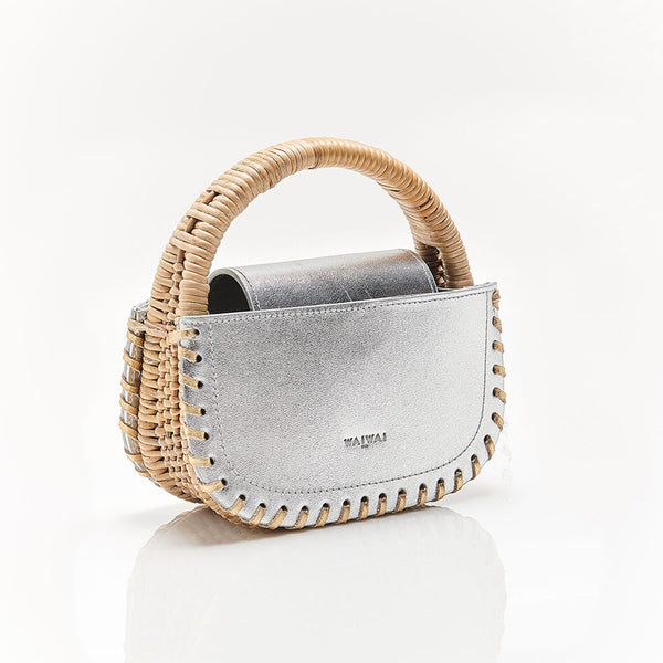 Bolsa estruturada em couro prateado, acabamento de costura nas bordas e alça em rattan rígido. Design moderno e sofisticado.