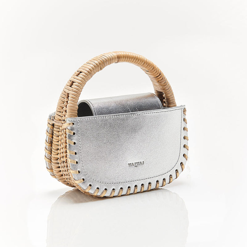 Bolsa estruturada em couro prateado, acabamento de costura nas bordas e alça em rattan rígido. Design moderno e sofisticado.