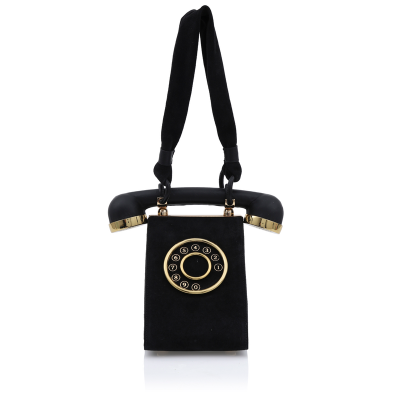 Bolsa preta em formato de telefone retrô com detalhe de disco dourado frontal e alça estruturada que imita o fone do aparelho.